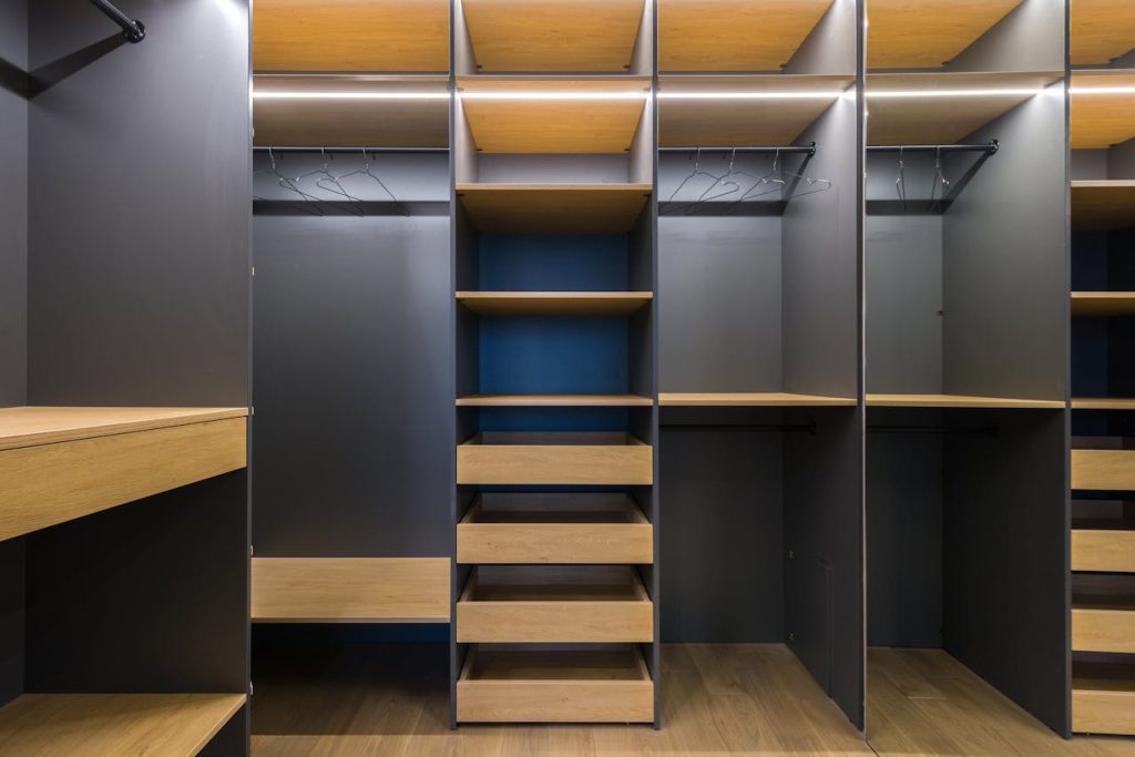 modern-wardrobe-storage-6580395 Spacious modern walk-in closet featuring wooden shelving and a sleek design, ideal for organization.