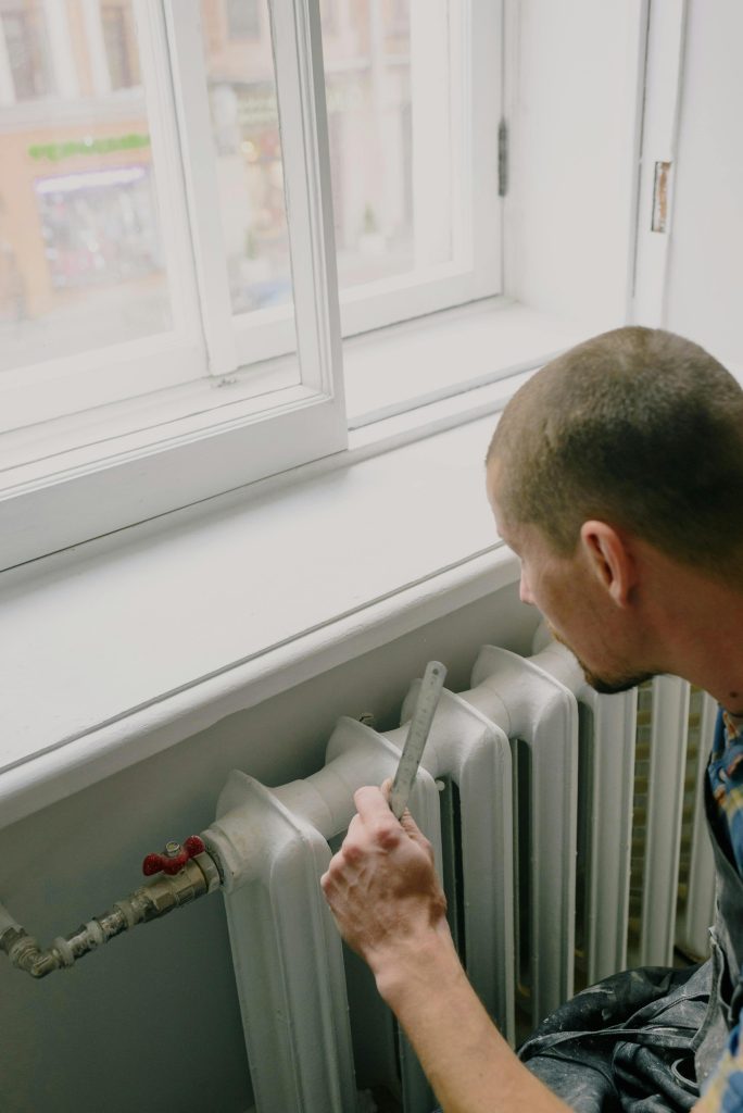 pexels-photo-5691536-5691536 From above side view of crop anonymous male worker with ruler near radiator and windowsill in house